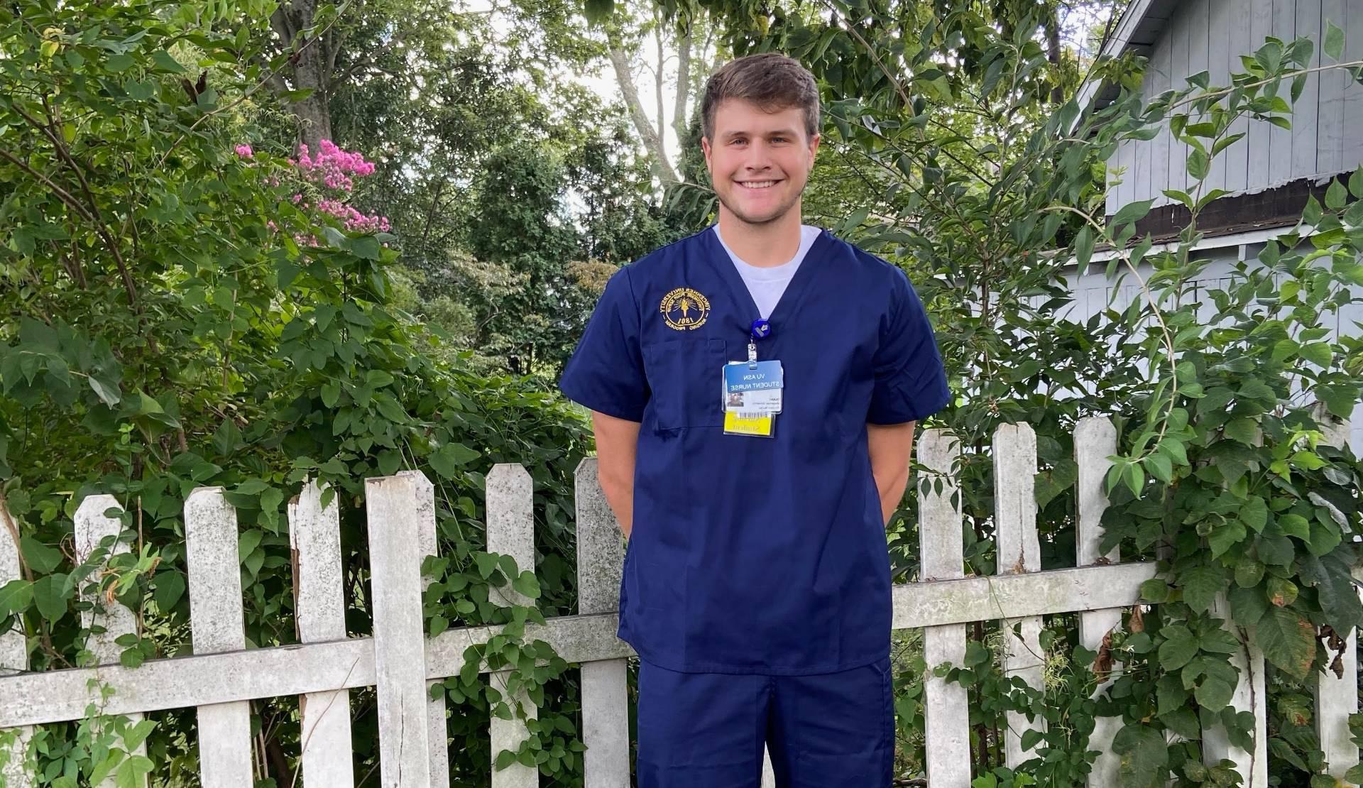 Isaac Lane posing for a photo in front of a fence